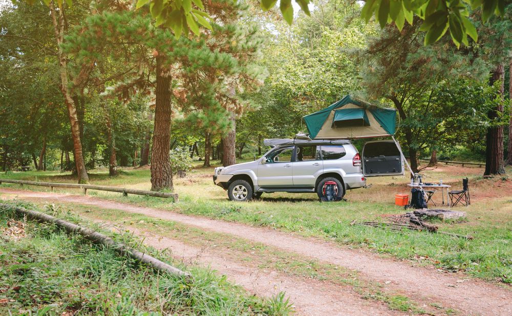 Side view of offroad 4x4 vehicle with tent on roof ready for camping
