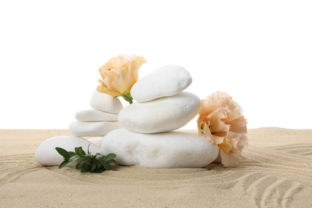 Stones and flowers on sand, isolated on plain background