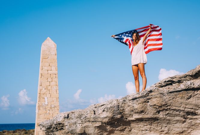 Peaceful patriotic female traveler enjoying in vacation at rocks