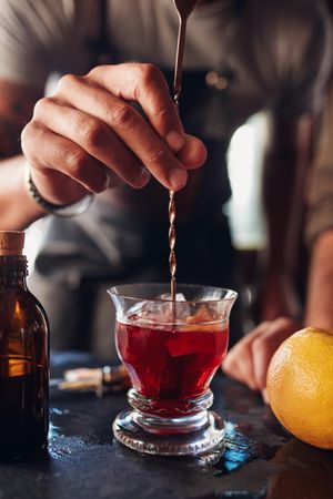 Closeup shot of bartender hand stirring a Negroni cocktail