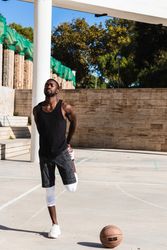 Black sportsman stretching on basketball court