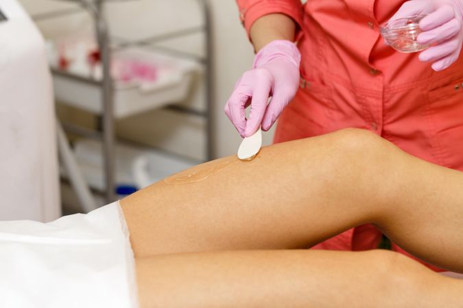 Cold gel applied to client’s leg before hair removal procedure