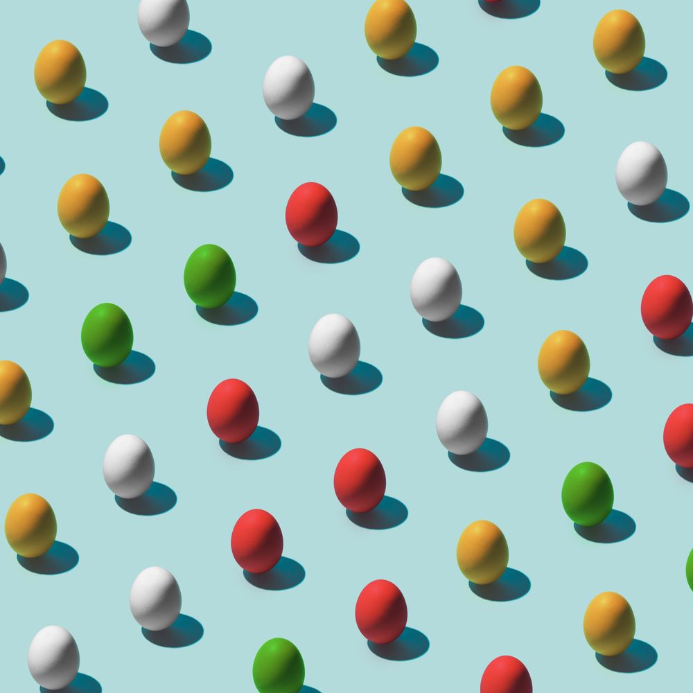 Pattern made of multi-colored eggs on pastel blue background