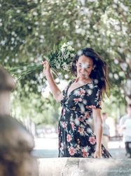 Young romantic female with bunch of flowers near fountain