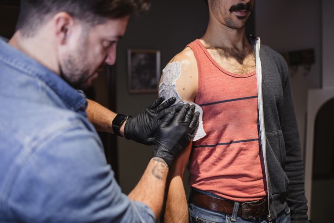 Tattoo master attaching stencil on forearm of client