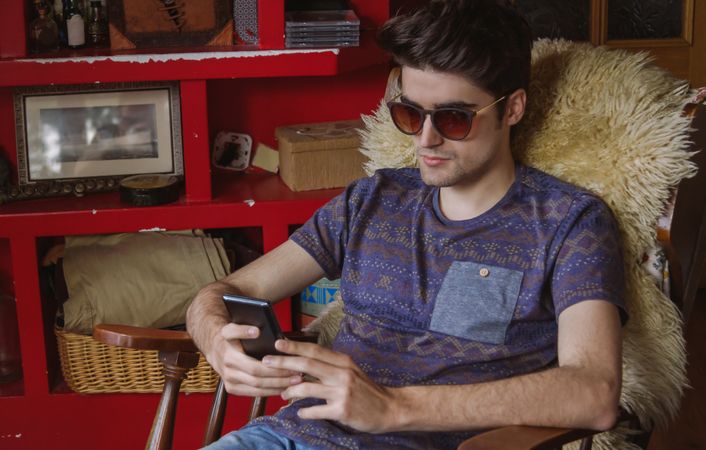 Young man looking smartphone sitting on chair