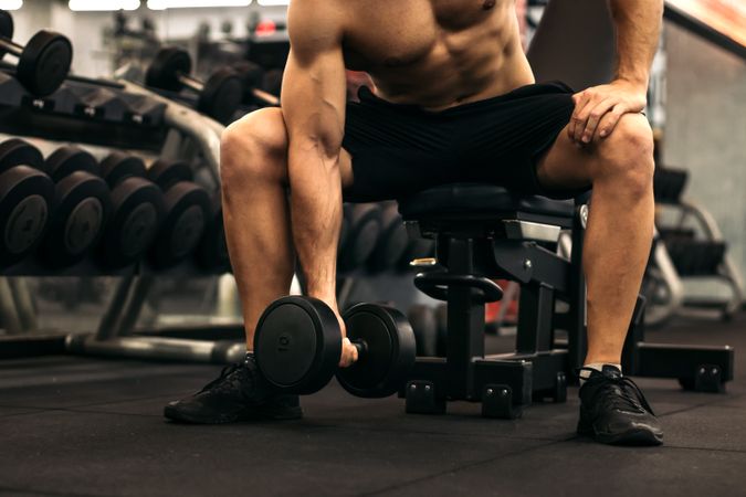 muscular man training arm with a dumbbell
