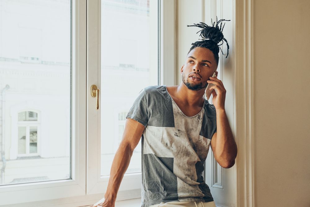 Black braided male using smartphone