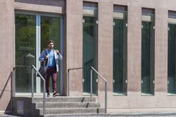 Businessman leaving office building while holding a shoulder bag outdoors