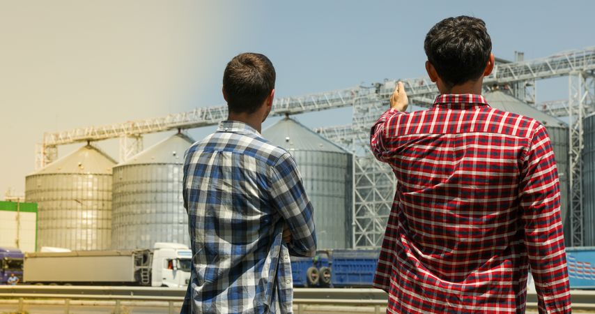 Two farmers against grain silos. Agriculture business