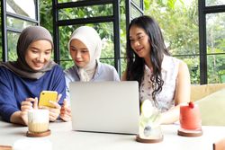 Three Asian Women Working with Laptop and Cell Phone in Cafe