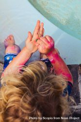Top view of blond boy washing pink paint off his hands with a sponge 5r1K10