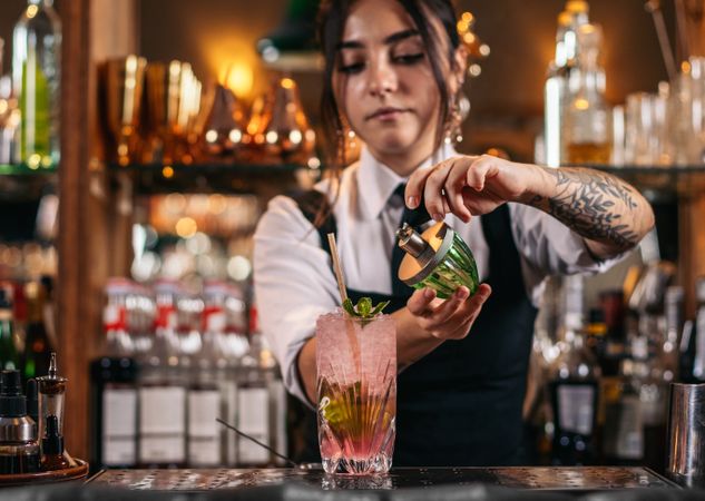 Female bartender preparing a cocktail in a traditional cocktail bar