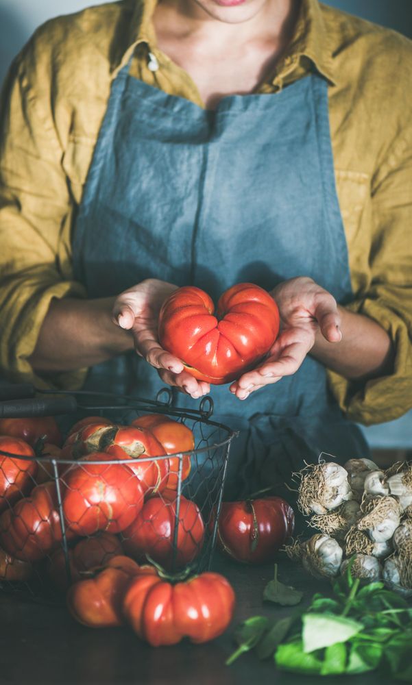 Woman in yellow holding large, heirloom with both hands