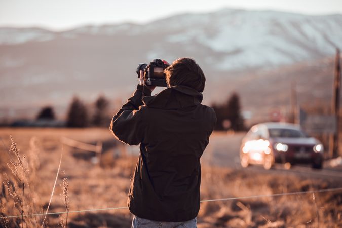 Man shooting on camera beautiful landscape between hills