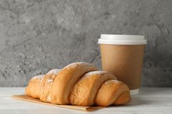 Cup of coffee and croissant on table, copy space