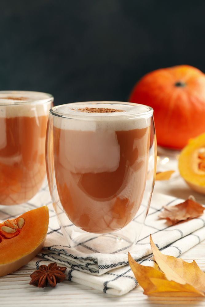 Composition with pumpkin latte on neutral wooden table