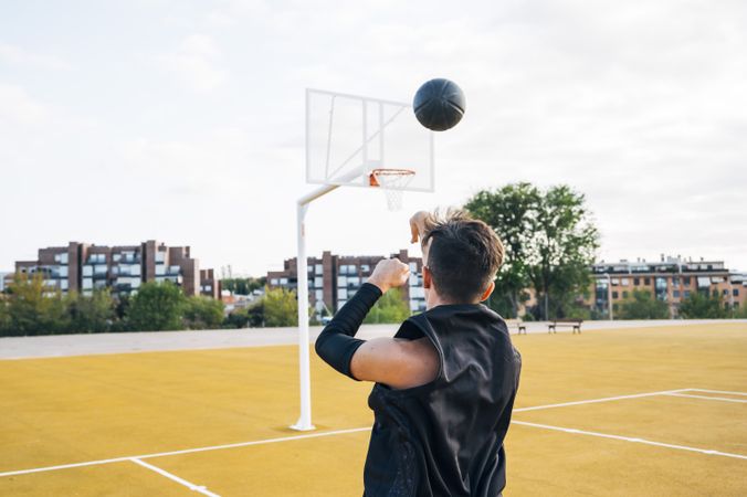 Young man playing on basketball court outdoor.