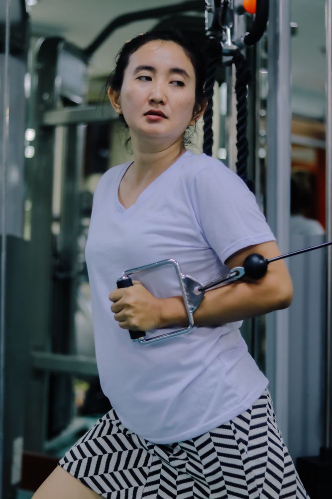 A woman uses a cable machine inside a fitness center