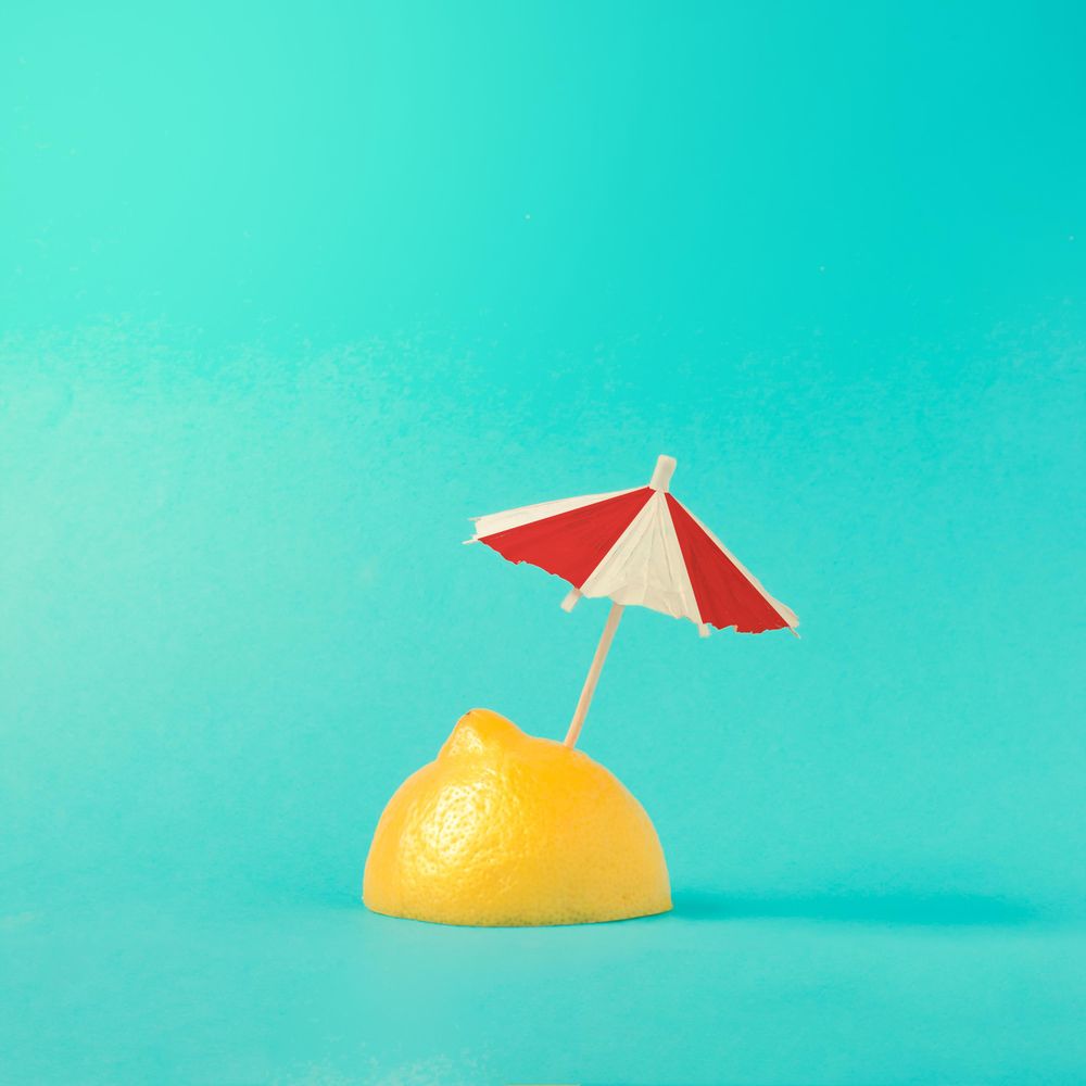 Lemon half with parasol on bright blue background