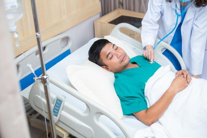 Physician treating sick man in hospital bed