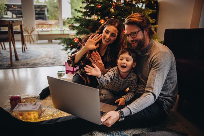 Family waving at laptop camera in video call for social distancing during Christmas