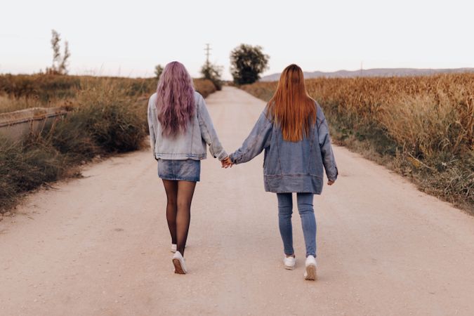 Strolling women holding hands in country