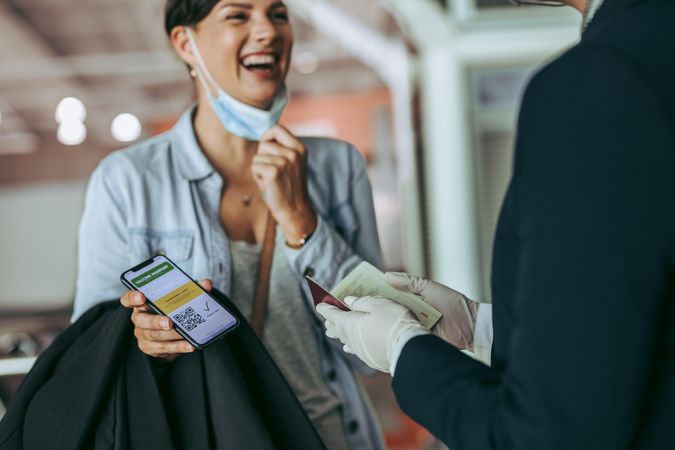 Woman traveler showing vaccine passport at check-in counter of airport