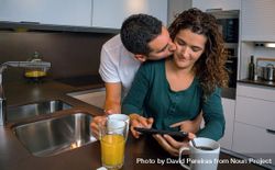 Affectionate couple reading digital table in kitchen at breakfast time 0WBwpb