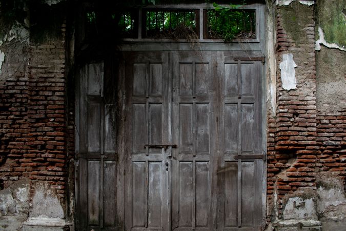 Big old broken wooden door on brick wall of historical building located in Kota Lama, Semarang City, Indonesia.