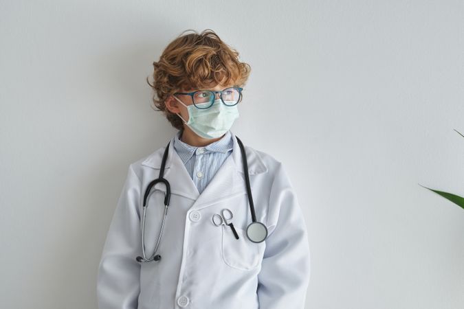 Dreamy boy in medical robe and sterile mask