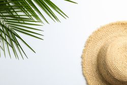Composition with straw hat and palm leaves on blank background. Top view, space for text