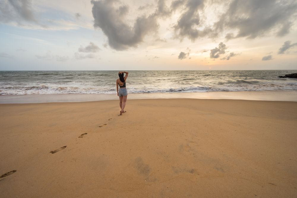 Woman in beachwear walking on sand barefoot