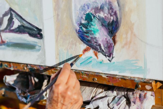 Anonymous woman painting on canvas in garden