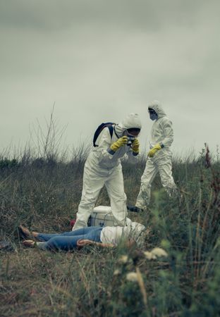 Man and woman in bacteriological protective suit taking a photo of a corpse