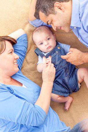 Young Couple Laying With Their Infant On A Blanket