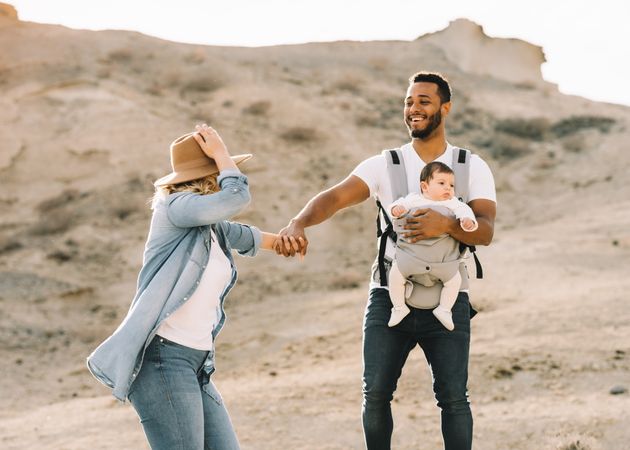 Diverse parents dancing while walking with baby