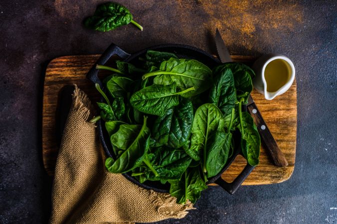 Top view of bowl of fresh spinach leaves on kitchen counter