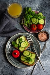 Top view of delicious lunch of bread with cucumber slices, tomatoes and Himalayan salt