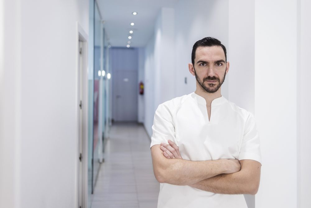 Portrait of a bearded doctor standing in the hospital hallway while looking camera