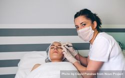 Woman receiving treatment on face in clinical center from aesthetician 0WOQ8O