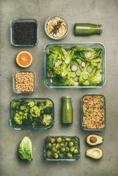 Variety of vegetable dishes arranged in glass containers with bottles of dressing