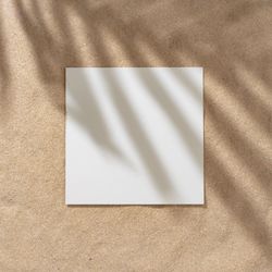 Sand with palm leaf shadows and central square