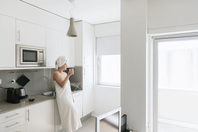 Pensive serene woman having refreshment with water in comfortable kitchen