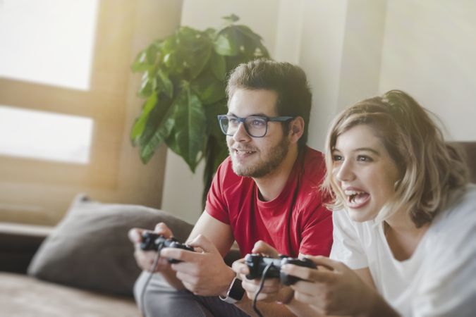 Couple with gamepads playing console