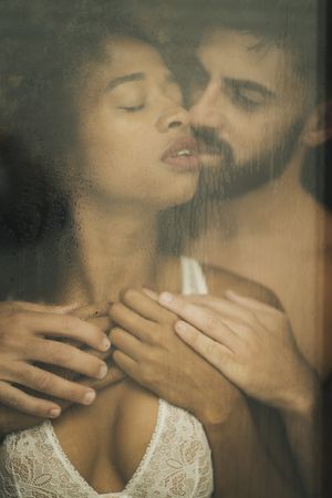 Bearded man touching girlfriend behind window