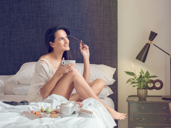 Delighted woman enjoying breakfast on bed