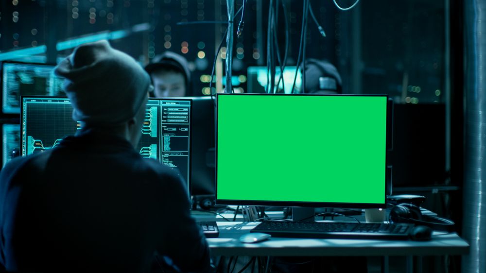 Shot of Hacker Working with Green Screen Mock-up Display Infecting Servers and Infrastructure with Malware.