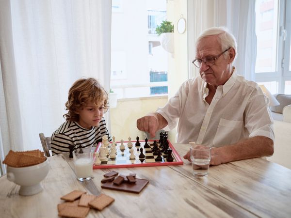 Grandfather and grandson playing board game at home
