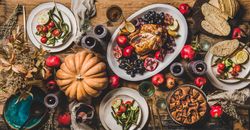 Autumnal table setting with squash, candles, roast chicken, pomegranate, fig pie and rose champagne